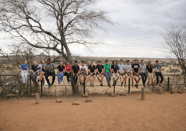 Sixth Form pupils sitting on fence in Africa