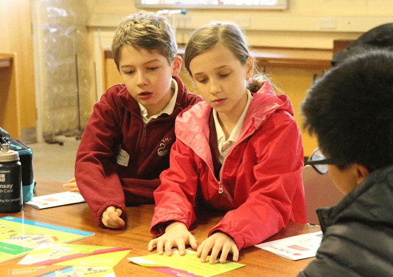 Pupils looking at cards on table at STEAM event