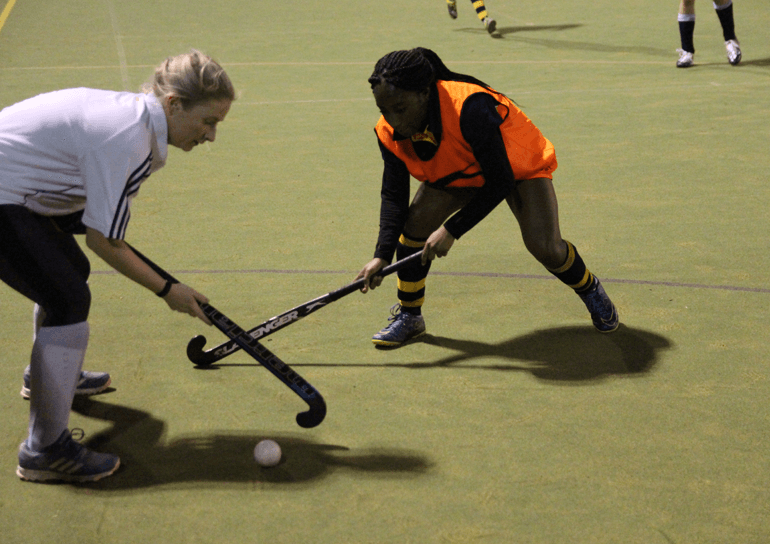 Two female pupils playing hockey
