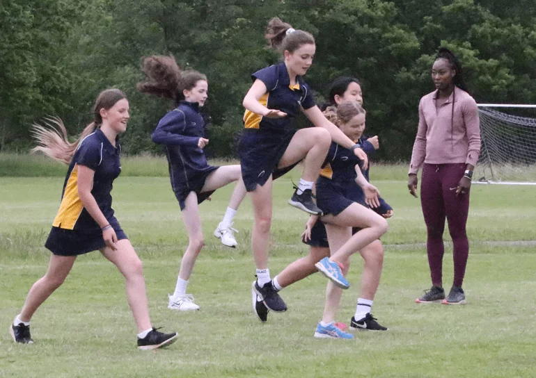 Leighton Park girls jumping outside with PE teacher