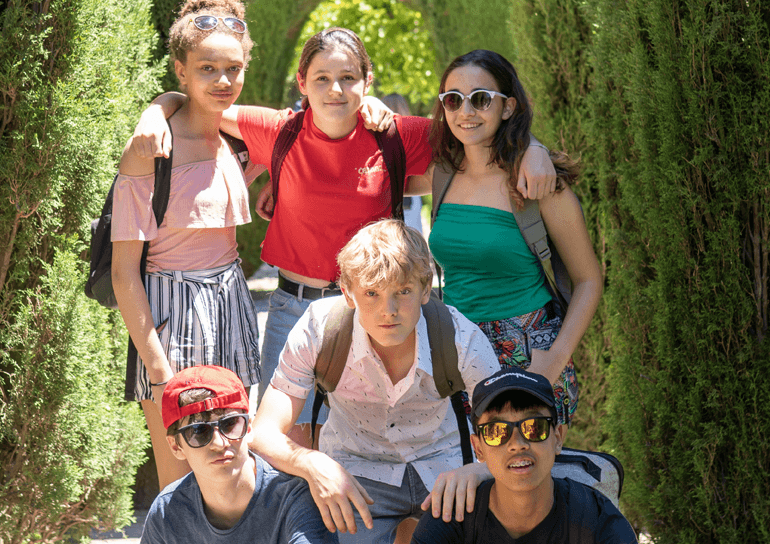 Five Leighton Park students in summer clothes in the sun surrounded by trees
