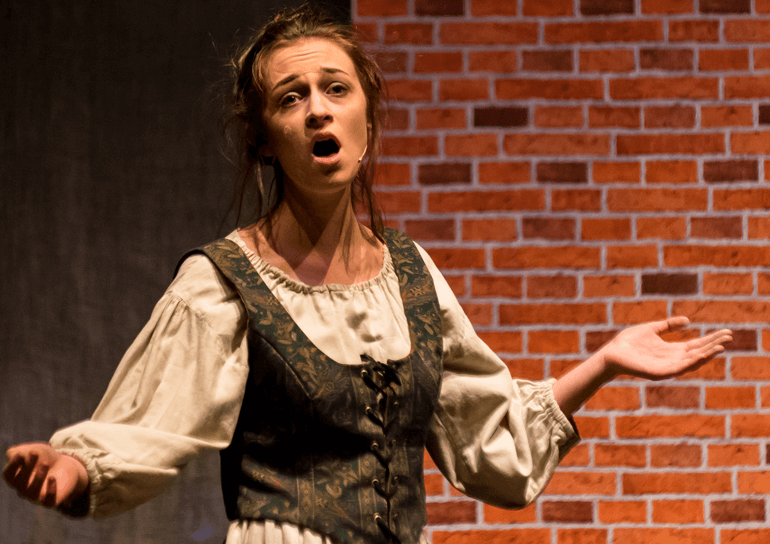 Woman singing on the stage dressed in rags