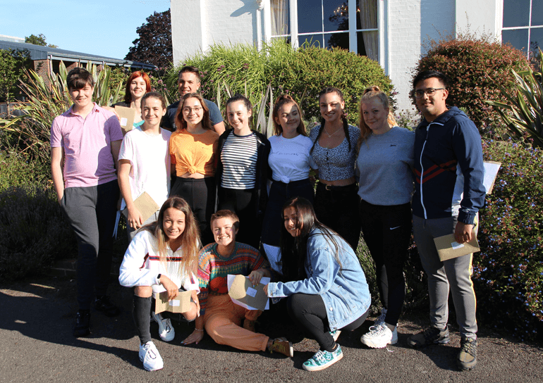 Thirteen Leighton Park GCSE students holding their results