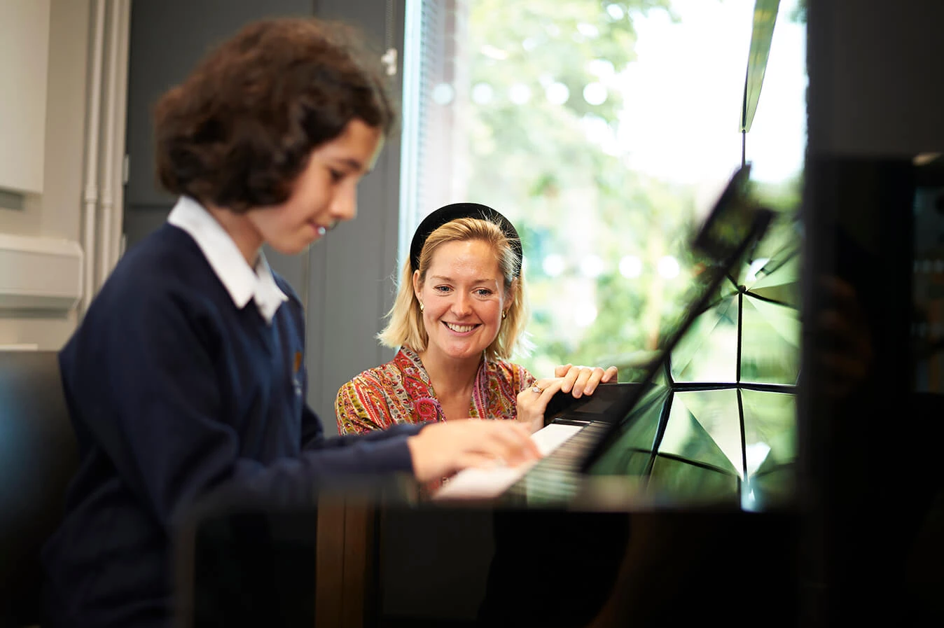 Teacher teaching piano to a girl