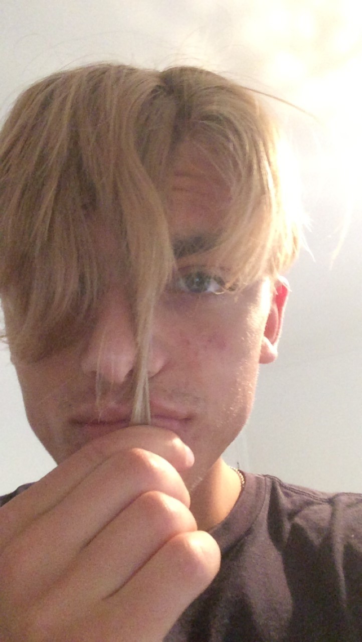 Zac pulling his blonde fringe down to his chin to show how long its grown