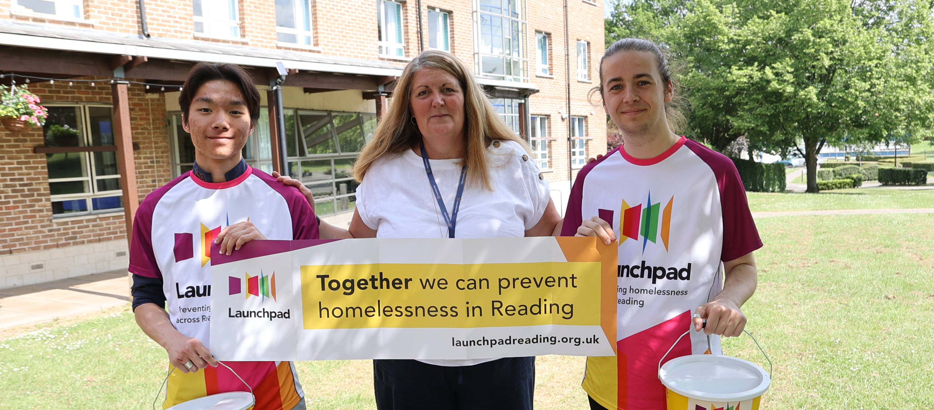 Woman and students holding charity banner and collection buckets